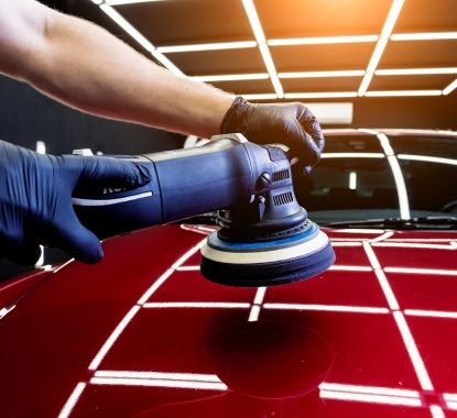 Car service worker polishes a car details with orbital polisher